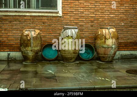 Antiche caraffe di argilla per vino, olio, con calderoni di rame sono esposti alla parete in mattoni del Museo d'arte e artigianato, al primo piano dell'Arme Foto Stock