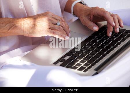 Primo piano ritratto di una donna anziana che scrive le mani sul computer portatile computer Foto Stock