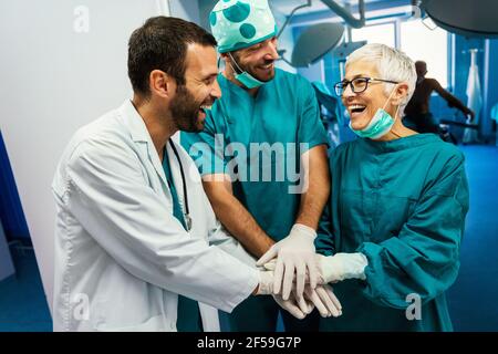 Sorridente medico che dà alto cinque dopo un intervento chirurgico riuscito. Sanità, successo, concetto medico Foto Stock