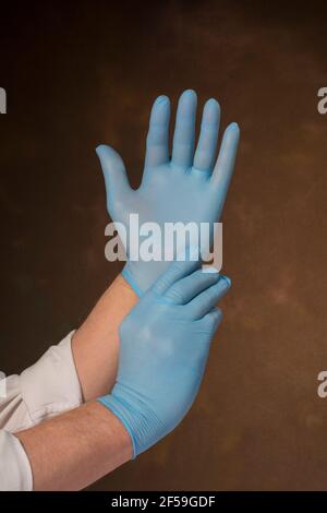 Uomo che indossa guanti blu chirurgici medici Foto Stock