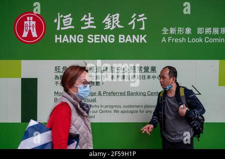 Hong Kong, Cina. 25 Marzo 2021. I pedoni passano accanto alla filiale della Hang Seng Bank e al logo di Hong Kong. (Foto di Budrul Chukrut/SOPA Images/Sipa USA) Credit: Sipa USA/Alamy Live News Foto Stock