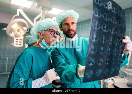 Team di medici chirurgo che guardano la pellicola a raggi X prima dell'intervento chirurgico per impostare la diagnosi Foto Stock