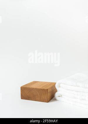 Podio vuoto in legno cubico per la presentazione dei prodotti. Espositore e salviette bianche su sfondo bianco. Vista frontale. Spazio di copia. Foto Stock