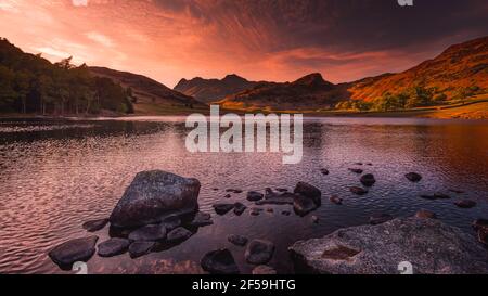 Tramonto su Blea Tarn nel Lake District, Cumbria, UK.tranquil paesaggio dell'ora d'oro con le montagne illuminate da sole setting.Beautiful sfondo della natura. Foto Stock