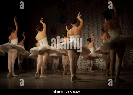 Ballerine in bianco tutus mostra movimento di danza. Le ragazze stanno facendo balletto. Lezione di ballo sul palco. Ci sono molte ragazze in abiti belli. GRA Foto Stock