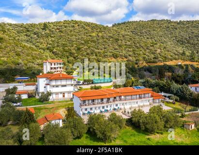 Vista dall'alto del drone aereo verso la Grecia campagna paesaggio estivo con case cittadine e case tetto in tegole rosse tra le verdi montagne della foresta, blu Foto Stock