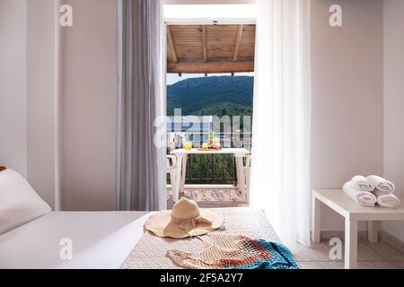 Closeup di porta aperta al balcone vista estate con mobili da terrazza, soffitto in legno, interno bianco della camera da letto vuota, in Europa apa lato campagna Foto Stock