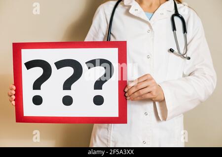 Immagine di una dottoressa che tiene un documento con un punto interrogativo. Foto Stock