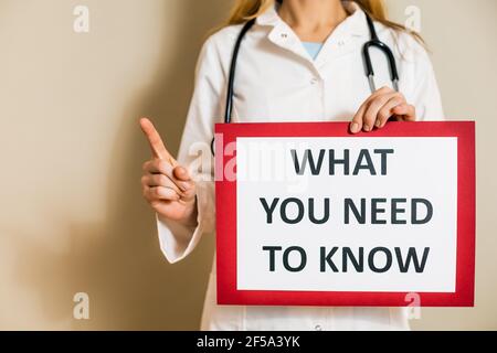 Immagine del medico femminile che tiene un documento con un testo che cosa dovete conoscere. Foto Stock
