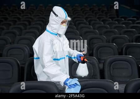 Sedie per la pulizia dei lavoratori con disinfettanti per gli amanti del cinema. Concetto di protezione contro covid-2019. Foto Stock