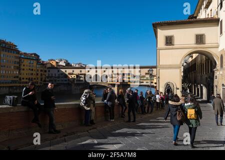 Passeggiata turistica lungo via Lungarno degli Archibusieri con il Ponte Vecchio sullo sfondo, Firenze, Toscana, Italia. Foto Stock