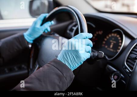 Mani del conducente in guanti di gomma blu che tengono il volante della vettura, vista ravvicinata Foto Stock