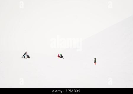 Ampio angolo di vista di Padre e bambino che dondolano giù un Ripida collina innevata Foto Stock