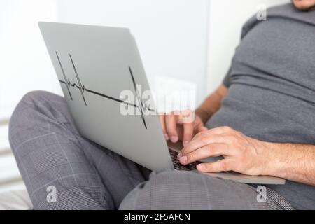 Un uomo lavora su un computer a letto da vicino mani Foto Stock