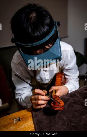 Giovane liutaio cinese al lavoro nel suo laboratorio Foto Stock