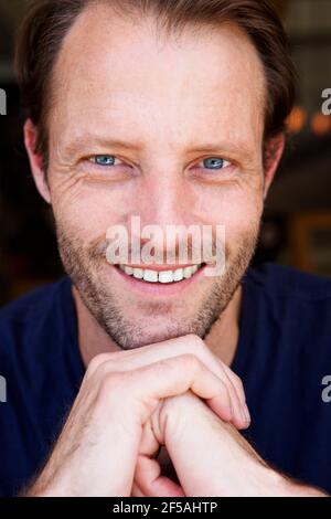 Primo piano ritratto di bell'uomo anziano sorridente con la mano al mento Foto Stock