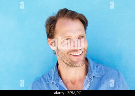 Primo piano ritratto di bell'uomo anziano sorridente contro il blu parete Foto Stock