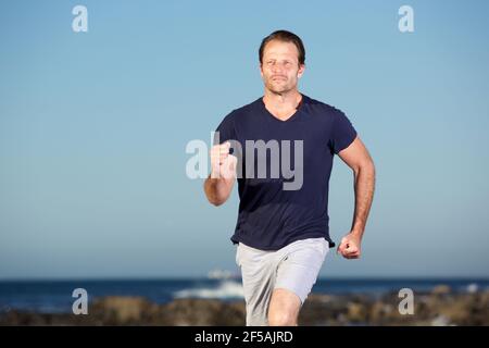 Ritratto di bell'uomo che corre all'aperto in spiaggia Foto Stock