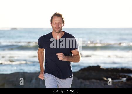 Ritratto di bell'uomo che corre fuori dalla spiaggia Foto Stock