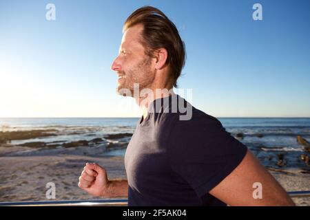 Ritratto laterale del corridore maschile fuori dalla spiaggia Foto Stock