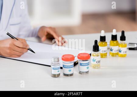 vista parziale del medico afroamericano che scrive la prescrizione sulla clipboard Foto Stock