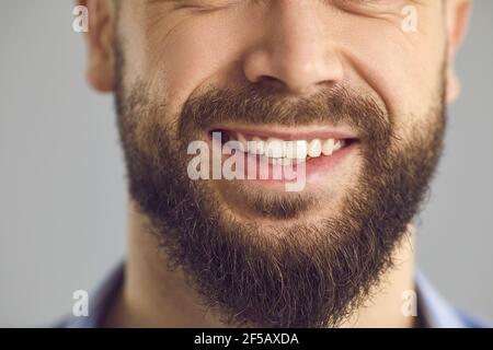 Primo piano studio di foto della parte inferiore del volto di felice giovane sorridente con barba marrone Foto Stock