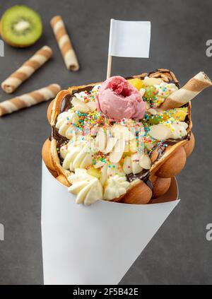 Hong kong o waffle a bolle con gelato, frutta, salsa al cioccolato e caramelle colorate Foto Stock