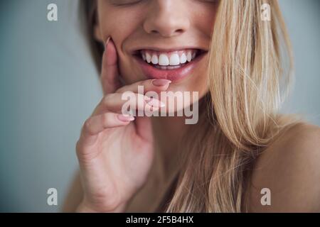 Donna con un sorriso togoteo che tocca la guancia con una mano Foto Stock