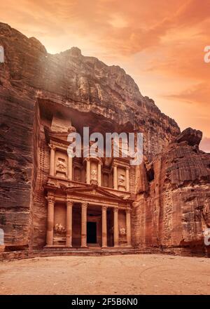 Davanti al tempio del Tesoro di al-Khazneh scolpito in muratura di pietra - attrazione principale nella città perduta di Petra, cielo arancione tramonto sopra Foto Stock