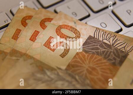 Banconote reali brasiliane - cinquanta banconote reais sulla tastiera di un computer. BRL in Brasile. Concetto di valuta, economia e affari. Foto Stock