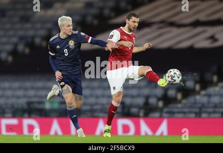 La Scozia Lyndon Dykes (a sinistra) e l'austriaco Aleksander Dragovic combattono per la palla durante la partita di qualificazione della Coppa del mondo FIFA 2022 a Hampden Park, Glasgow. Data immagine: Giovedì 25 marzo 2021. Foto Stock