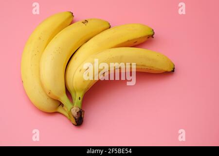 Un mazzo di banane su uno sfondo rosa vista dall'alto. Banane mature con spazio per la copia. Foto Stock