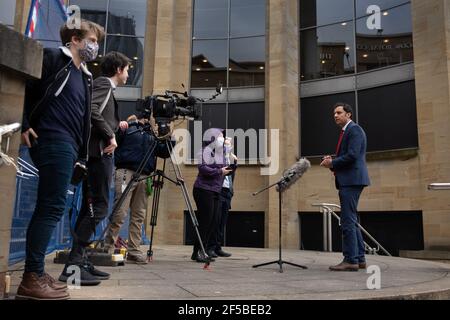 Glasgow, Regno Unito. 25 Marzo 2021. ANAS Sarwar, leader del Partito laburista scozzese, promuove il messaggio elettorale del suo partito C un piano di ripresa nazionale, accanto alla statua dell'ex leader laburista scozzese e primo ministro, Donald Dewar, a Glasgow. Photo Credit: jeremy sutton-hibbert/Alamy Live News Foto Stock