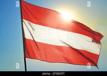 Bandiera austriaca che sventola sul vento davanti al sole Foto Stock