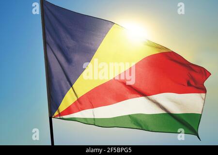 Bandiera delle Seychelles sventolando sul vento di fronte al sole Foto Stock