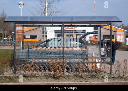 Le coppie anziane in un supermercato caricano i loro generi alimentari nella macchina. In primo piano una capanna coperta del carrello della spesa Foto Stock