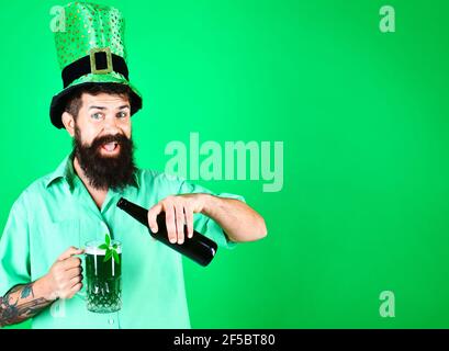 San Patrizio giorno. L'uomo sorridente bearded nel cappello di leprechaun versa la birra in vetro. Foto Stock