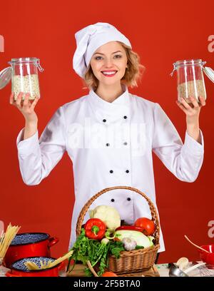 Cuoco professionale in uniforme bianca con vasetti e cereali. Cucina e preparazione alimentare. Foto Stock