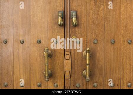 Particolare di una porta in legno con borchie, con pomelli in ferro e battitori a mano Foto Stock