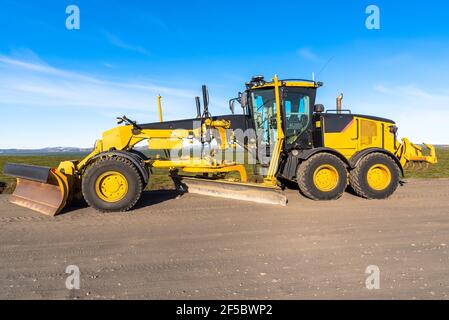 Motorgrader in un cantiere stradale sotto cielo blu Foto Stock