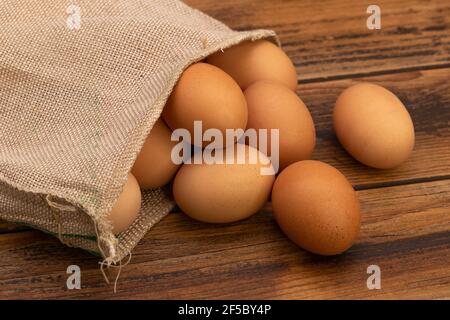 Uova di pollo marroni in sacco su un tavolo rustico in legno. Foto Stock