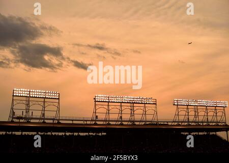 Chicago, Illinois, Stati Uniti. Il sole tramonta oltre le torri faro sulla tribuna di Wrigley Field durante una partita notturna. Foto Stock