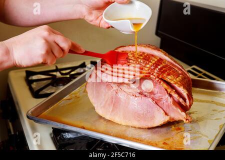 Preparazione del prosciutto di maiale affettato a spirale con glassa al miele. Foto Stock