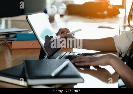 Uomo d'affari che usa la penna elettronica mentre lavora, mano dell'uomo che usa la penna dello stilo con il tablet mentre fa il calcolo finanziario alla sua scrivania dell'ufficio. Foto Stock