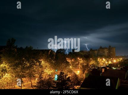 Fulmine temporale sopra la città di notte. Molte luci sopra la tenuta di alloggiamento. Tempesta notturna in città. Scatto a esposizione lunga. Foto Stock