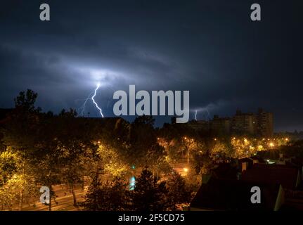 Fulmine tempesta sulla città di notte. Molte luci sopra la tenuta di alloggiamento. Tempesta notturna in città. Scatto a esposizione lunga. Foto Stock