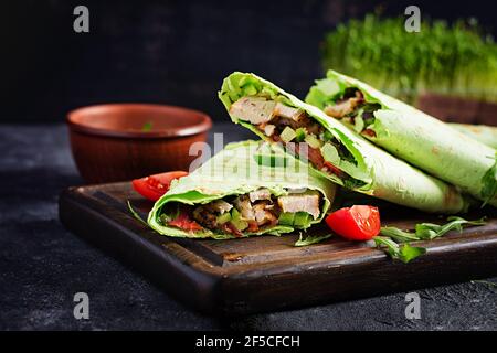 Tortilla fresche con pollo e verdure fresche su tavola di legno. Burrito di pollo. Concetto di cibo sano. Cucina messicana. Foto Stock