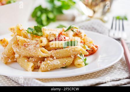 Fetapasta. Ricetta di tendenza per la pasta alla torta Feta fatta di pomodori ciliegini, formaggio feta, aglio ed erbe. Foto Stock
