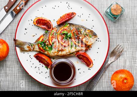 Pesce Dorado al forno con salsa di pompelmo. Pesce arrosto su un piatto. Foto Stock