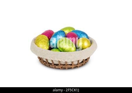 Uova di Pasqua colorate avvolte in foglio in cestino isolato su sfondo bianco. Foto Stock